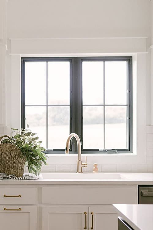 A bright kitchen with dark framed windows and a view beyond